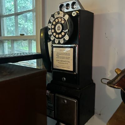 Sale Photo Thumbnail #82: Vintage wall-mounted 3-slot rotary payphone in black metal casing with chrome trim, complete with coin slots, receiver, and instructional plaque.