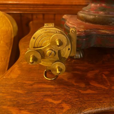 Sale Photo Thumbnail #135: Antique brass nautical or surveying instrument base, featuring adjustable leveling feet and intricate mechanical dials.