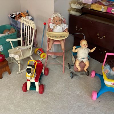 Sale Photo Thumbnail #188: Collection of vintage children's toys and dolls, featuring a Playskool walker, a wooden rocking horse, vintage baby dolls with a high chair and stroller, and a small child's rocking chair.