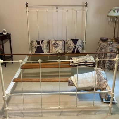 Sale Photo Thumbnail #215: Vintage white painted wrought iron and brass bed frame with wooden slats, displayed alongside floral linens and accent furniture.
