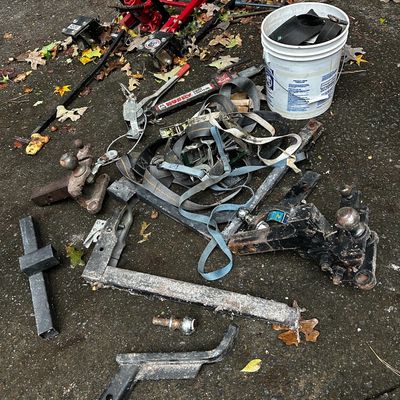 Sale Photo Thumbnail #42: Collection of towing accessories and equipment, including a red hydraulic motorcycle lift, trailer hitches, ball mounts, sway control bar, and ratchet straps.