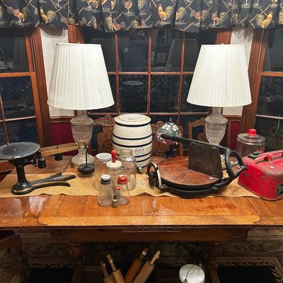 Sale Photo Thumbnail #21: Collection of vintage kitchenware and home decor displayed on a wooden table, including a balance scale, stoneware crock, glass lamps, and a cast iron tobacco cutter.