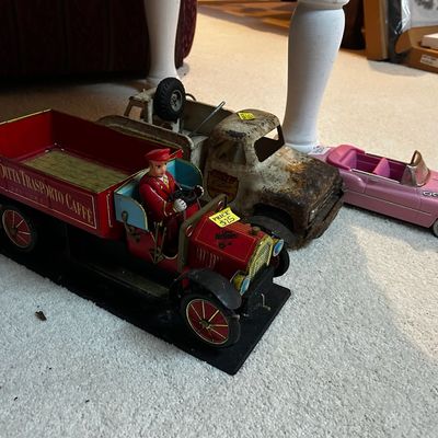 Sale Photo Thumbnail #44: Collection of vintage toy vehicles, including a red Italian coffee delivery tin truck, a heavily weathered metal wrecker truck, and a pink classic convertible car.