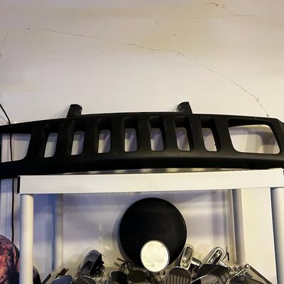 Sale Photo Thumbnail #18: Black matte front grille panel, likely for a Hummer H3, sitting atop a white shelving unit with automotive accessories below.