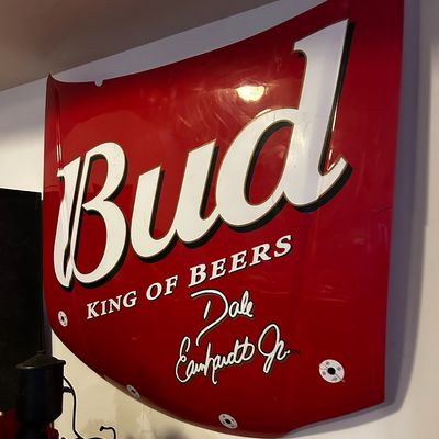 Sale Photo Thumbnail #24: NASCAR sheet metal stock car hood sign featuring Budweiser branding and Dale Earnhardt Jr. graphics, mounted on a wall.