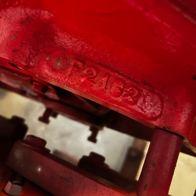 Sale Photo Thumbnail #51: Close-up of a red painted metal machine part showing a stamped serial number F2132.