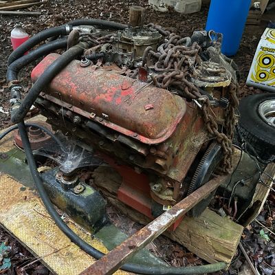 Sale Photo Thumbnail #114: Vintage V8 engine block wrapped in heavy rusted chain, sitting on a wooden pallet outdoors.