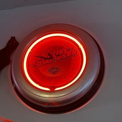 Sale Photo Thumbnail #88: Harley-Davidson neon wall clock with a silver-tone casing and orange-red illumination.