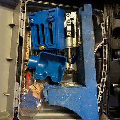 Sale Photo Thumbnail #29: Kreg pocket hole jig system kit housed inside a grey plastic storage case with wooden dowels and accessories.