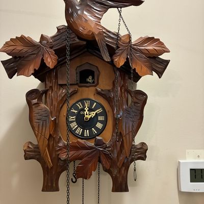 Sale Photo Thumbnail #212: Hand-carved Black Forest style cuckoo clock featuring intricate bird and maple leaf motifs with hanging chains.