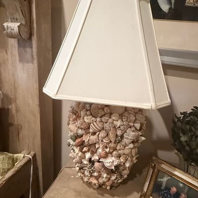Sale Photo Thumbnail #233: Coastal-style table lamp featuring an urn-shaped base entirely encrusted with natural sea shells, paired with an off-white hexagonal lampshade.