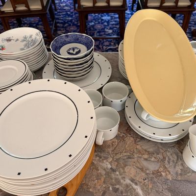 Sale Photo Thumbnail #3: Assorted vintage table ceramic dishware, including modern black-dotted dinner plates, blue-and-white bowls, and a large yellow oval serving platter.