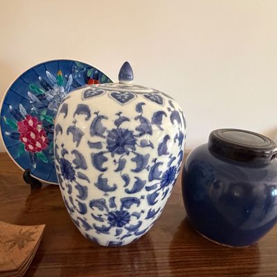 Sale Photo Thumbnail #12: Collection of Asian ceramic items including a blue and white patterned ginger jar with lid, a solid cobalt blue jar with wooden lid, and a floral display plate.