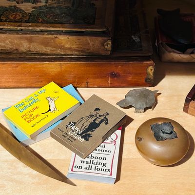 Sale Photo Thumbnail #12: Collection of vintage novelties including miniature flip books, a brass letter opener, a persimmon-shaped censer, and a small wooden box.