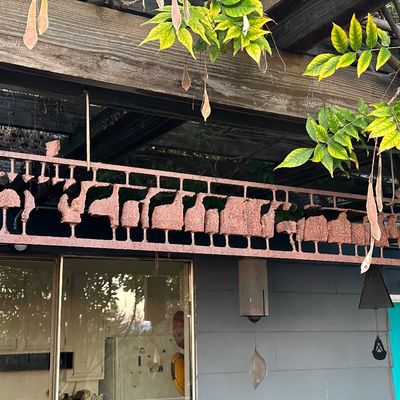 Sale Photo Thumbnail #144: Rustic, heavily rusted wrought iron horizontal garden wall art panel featuring silhouette figures, suspended outdoors from a wooden pergola.