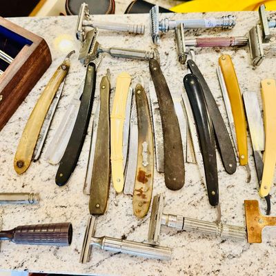 Large collection of vintage safety razors and straight razors, featuring various celluoid and bone-handled pieces alongside classic metal...