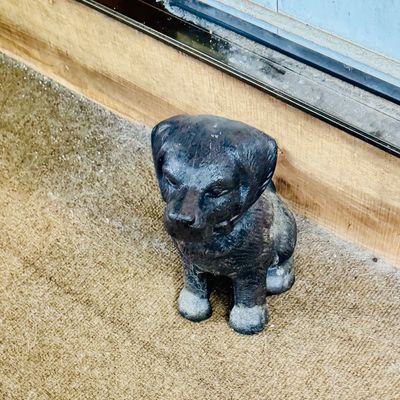 Cast iron dog doorstop depicting a sitting puppy, showing minor surface wear and patina.