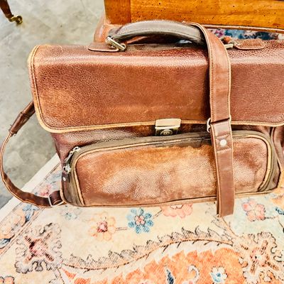 Sale Photo Thumbnail #32: Vintage distressed brown leather briefcase with top handle, shoulder strap, and front zippered pouch, showing natural wear.