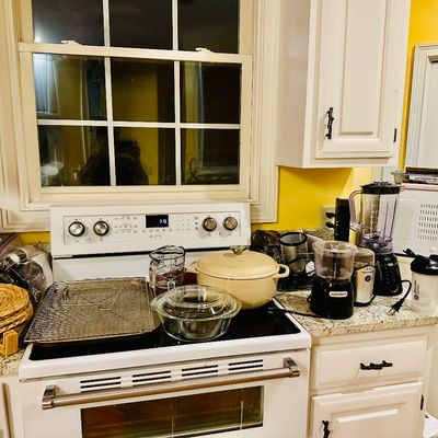Sale Photo Thumbnail #96: Kitchen counter assortment featuring small appliances including a Keurig coffee maker, Hamilton Beach food processor, Oster blender, and a white microwave, alongside cookware and glassware.