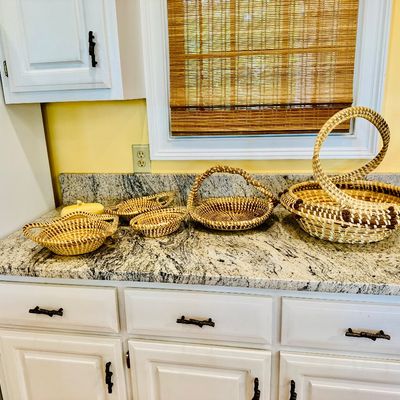 Sale Photo Thumbnail #25: Collection of handwoven sweetgrass baskets in various sizes and styles, displayed on a granite countertop.