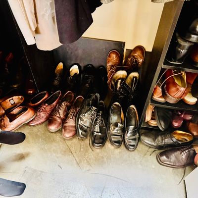 Sale Photo Thumbnail #48: Collection of men's leather dress shoes, loafers, and boots arranged on the floor and a black shelving unit.