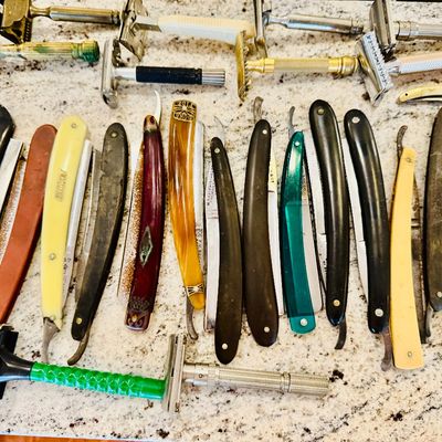 Large collection of vintage safety razors and straight razors featuring various handle materials and metallic finishes.