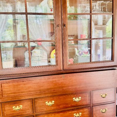 Traditional mahogany china hutch featuring glass paned upper doors, interior lighting, and lower drawers with brass hardware.