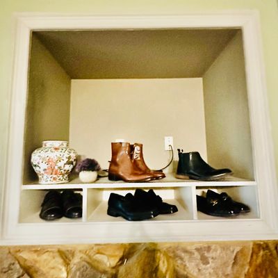 Sale Photo Thumbnail #90: A built-in display nook featuring brown leather boots, black Chelsea boots, loafers, and a floral ceramic ginger jar.