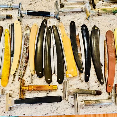Large collection of vintage straight razors and safety razors with various handles and finishes.