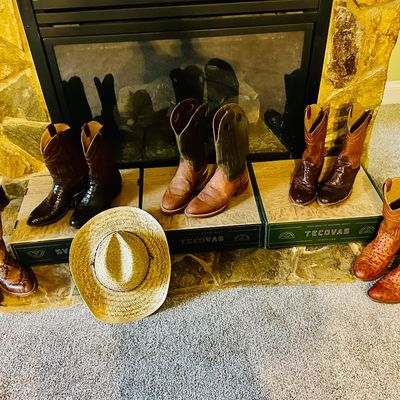 Sale Photo Thumbnail #89: Collection of five pairs of men's western cowboy boots, including Tecovas brand and exotic leather styles, displayed with a woven straw cowboy hat.