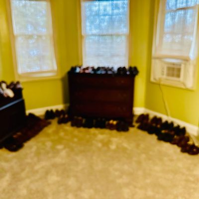 Sale Photo Thumbnail #80: Collection of men's dress shoes displayed along the floor and atop dark wood bedroom dressers in a carpeted room.