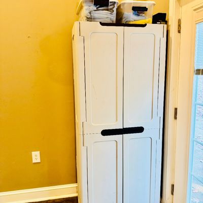 Sale Photo Thumbnail #52: Tall white resin storage cabinet with black handles, topped with clear plastic storage totes filled with linens.