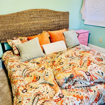 Sale Photo Thumbnail #70: Woven seagrass or rattan arch headboard paired with a colorful orange, teal, and cream paisley bedding set and accent pillows.