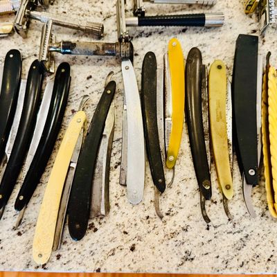 Large collection of vintage straight razors and double-edge safety razors featuring various handle materials like celluloid, bakelite,...