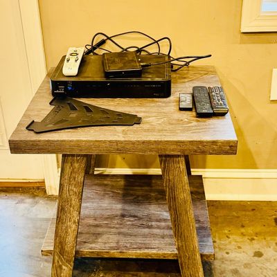Sale Photo Thumbnail #33: Rustic weathered grey wood side table with a bottom shelf, holding electronics including a DIRECTV DVR, media player, and remote controls.