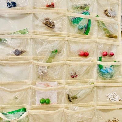 Sale Photo Thumbnail #28: Hanging clear pocket jewelry organizer filled with various pairs of costume earrings and small accessories.