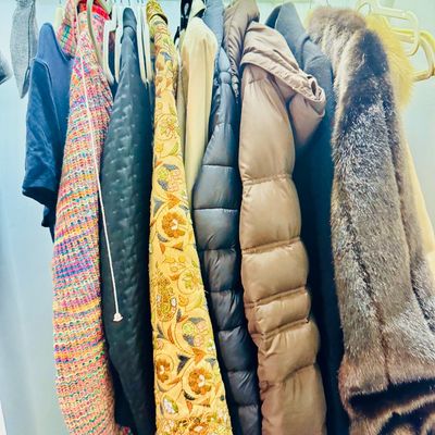Sale Photo Thumbnail #76: Closet rod featuring an assortment of women's outerwear, including puffer jackets, an embroidered coat, and a fur garment.