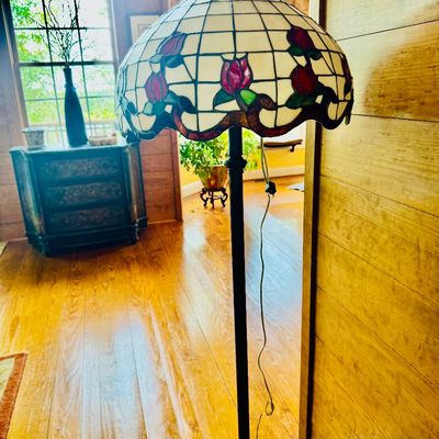 Sale Photo Thumbnail #61: Tiffany-style stained glass floor lamp featuring a floral rose design on a cream geometric grid, mounted on a dark metal base.