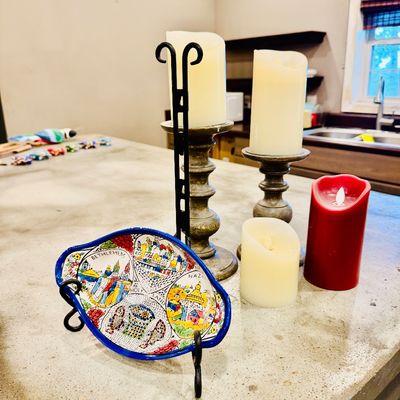 Sale Photo Thumbnail #60: Hand-painted Armenian ceramic souvenir dish featuring Holy Land sites on a display stand, shown alongside pillar candles on wooden holders.