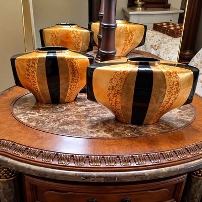 Sale Photo Thumbnail #87: Set of decorative Art Deco style ceramic vases featuring black, orange, and metallic gold striped patterns, displayed on a marble-top accent table.