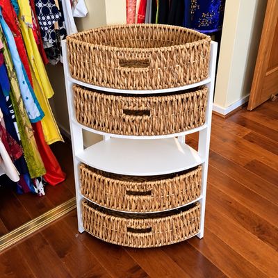 Sale Photo Thumbnail #86: Contemporary white wooden corner storage unit featuring four tiers, equipped with woven water hyacinth basket drawers.