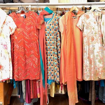 Sale Photo Thumbnail #65: Collection of colorful women's South Asian garments, including embroidered tunics, salwar kameez suits, and matching scarves, displayed on a closet hanging rod.