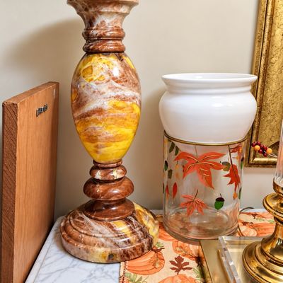 Sale Photo Thumbnail #81: Tall carved marbled onyx pedestal candlestick alongside an autumnal painted glass and ceramic vessel.