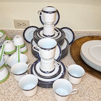 Sale Photo Thumbnail #90: Vintage white fine china dinnerware service featuring navy blue floral borders and accents, alongside green-accented Asian soup bowls and porcelain spoons.