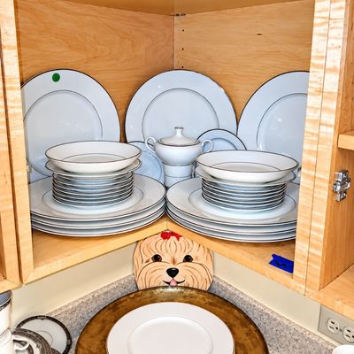 Sale Photo Thumbnail #93: Collection of fine white porcelain dinnerware featuring silver rims stacked in a wooden corner cabinet.
