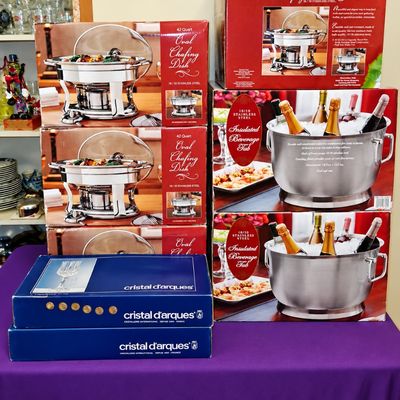 Sale Photo Thumbnail #96: Stack of new-in-box entertaining supplies, including multiple stainless steel oval chafing dishes, insulated beverage tubs, and boxed Cristal d'Arques glassware.
