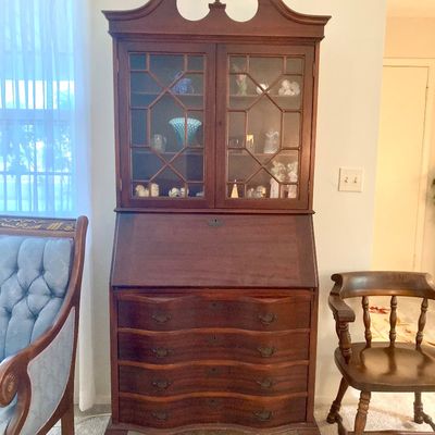 Traditional Chippendale-style mahogany secretary desk featuring a broken-pediment bonnet top with finial, glass-front display cabinet,...