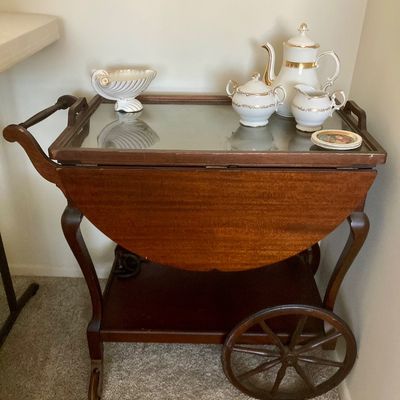 Sale Photo Thumbnail #192: Vintage drop-leaf mahogany tea cart with a glass inset top and large wooden wheels.


