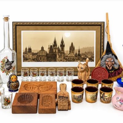 Sale Photo Thumbnail #24: Collection of vintage decor items including a framed Prague skyline print, rifle-shaped glass bottles, matching shot glasses with animal motifs, carved wooden molds, ceramic figurines, and hand-painted glassware.