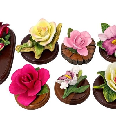 Sale Photo Thumbnail #7: Collection of seven hand-painted porcelain flower figurines mounted on wooden display bases, including various roses, orchids, and a magnolia in vibrant colors.